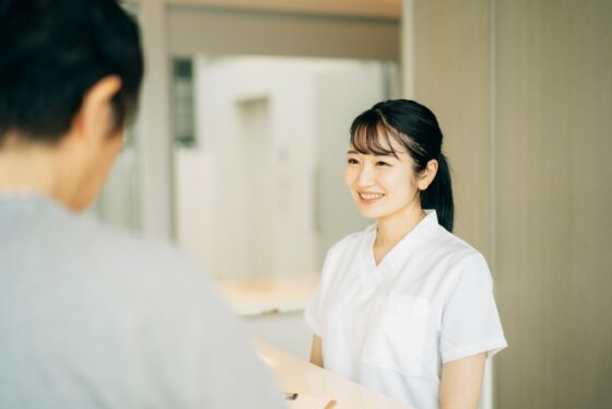 歯科医院の受付で患者様に笑顔で対応するスタッフ